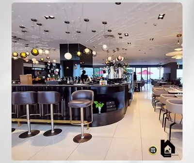 a restaurant with a bar with stools at Deluxe Studio good for 3 adults in Novotel Suites Manila with City View in Manila