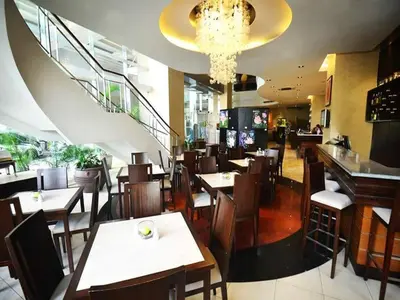 a restaurant with tables and chairs and a staircase at Lancaster Hotel Manila in Manila