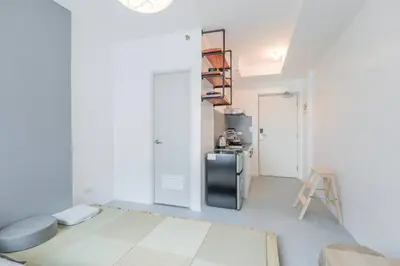 a white living room with a refrigerator and a table at Japanese Stylish Condo in Makati in Manila
