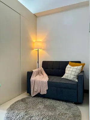 a living room with a blue couch and a lamp at Cozy and Homey 1BR Condo at SMDC South Residences in Manila