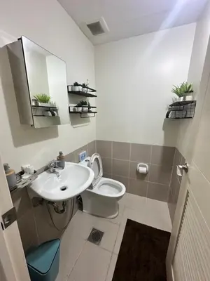 a bathroom with a sink and a toilet and a mirror at Prisma Residences Astra Building in Manila