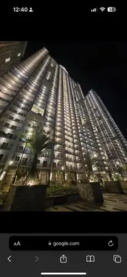 a large building is lit up at night at Prisma Residences Astra Building in Manila