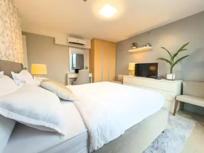 a bedroom with a white bed and a television at 1BR BGC, One Uptown Residence B001 in Manila
