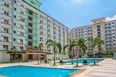 a large apartment building with a swimming pool and palm trees at Chill in Peace Staycation 2BR condo at Field Residences, Sucat near NAIA in Manila