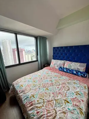 a bedroom with a large bed and a large window at Comfy Relax Condo at the Rise Makati in Manila
