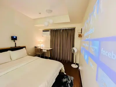 a hotel room with a bed and a wall with a screen at NEW! Studio Condo in Prisma Residences Pasig in Manila