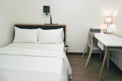 a bedroom with a white bed and a desk at NEW! Studio Condo in Prisma Residences Pasig in Manila