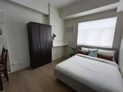 a bedroom with a large bed and a window at Vista GL Taft Studio Unit in Manila