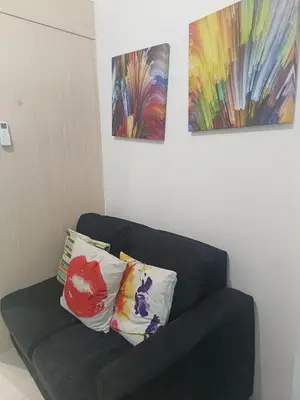 a black couch with two pillows and two paintings at SEA RESIDENCES NEAR MALL OF ASIA BY Amigo's place in Manila