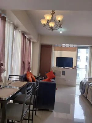 a living room with a couch and a table and a tv at Emy Cozy Studio unit with street view balcony in Manila