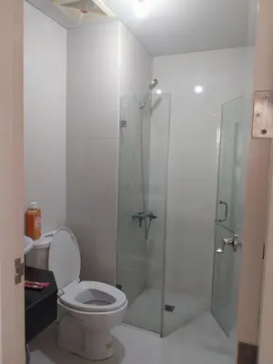 a bathroom with a toilet and a glass shower at Emy Cozy Studio unit with street view balcony in Manila