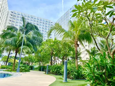 a park with palm trees in front of a tall building at MOA SHORE - Exxy SUITES in Manila