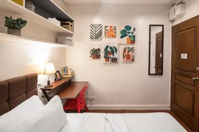 a bedroom with a bed and a desk with a lamp at Homey and Cozey Poblacion Makati S05 in Manila