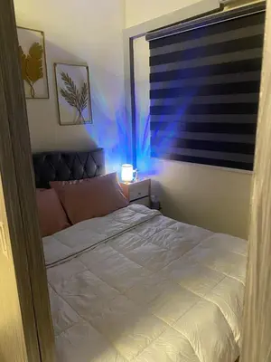 a bedroom with a bed and a window with blue light at Cozy Urban Apartment in Pasay City in Manila