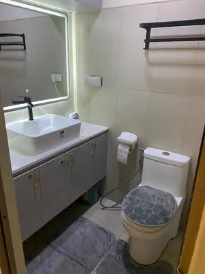 a bathroom with a sink and a toilet and a mirror at Cozy Urban Apartment in Pasay City in Manila