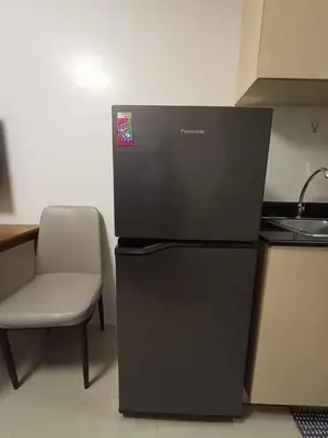 a refrigerator in a kitchen with a chair and a sink at Sea Residences Staycation MOA Pasay in Manila
