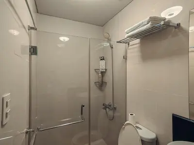 a bathroom with a glass shower and a toilet at One Palm Tree Condominium in Manila
