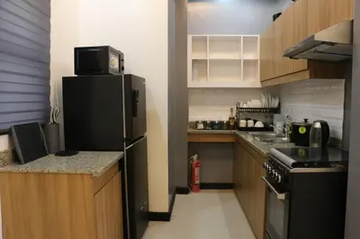 a small kitchen with a refrigerator and a stove at Kapitolyo Prisma Residential Condo TCPH21 - NYC Vibes Penthouse with KTV Pool and Balcony with City View Panorama 5 Min Drive to BGC St Lukes and Ortigas - Staycations by SMS in Manila