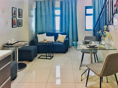 a living room with a blue couch and a table at Best Value Stylish Loft Steps from Greenbelt Mall in Manila