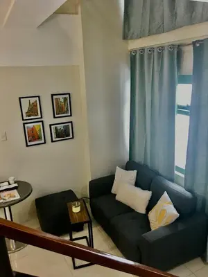 a living room with a couch and a window at Best Value Stylish Loft Steps from Greenbelt Mall in Manila