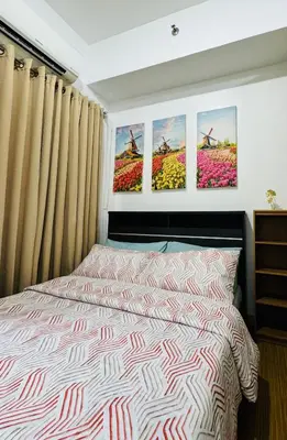 a bedroom with a bed and three paintings on the wall at LD Cozy Condo - Grace Residences, Taguig City near BGC in Manila