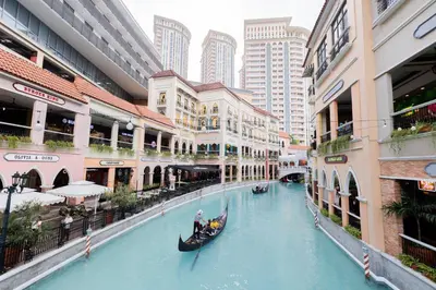 a gondola rides down a canal in a city at LUXX BGC Venice in Manila
