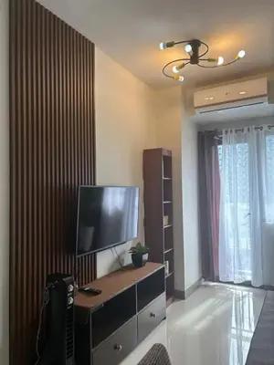 a living room with a tv and a dresser with a television at Cozy Condo Stay Near MOA in Manila