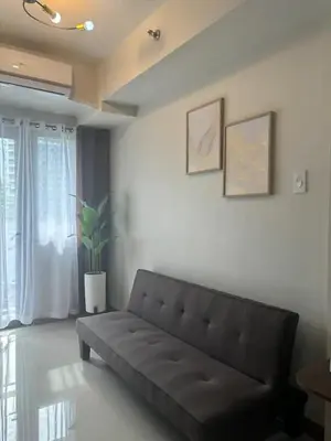 a living room with a black couch and a window at Cozy Condo Stay Near MOA in Manila