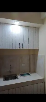 a kitchen with a sink and white cabinets at Bahay ni Ate Rose in Manila
