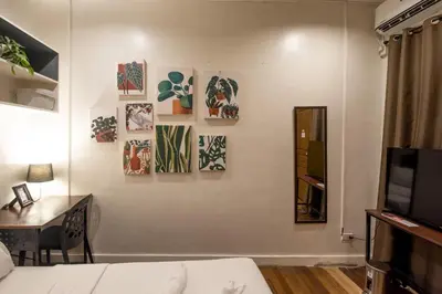 a living room with a couch and a table and paintings on the wall at Homey and Cozey Poblacion Makati S12 in Manila