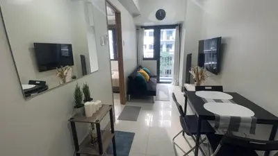 a living room with a table and a dining room at Casa Liandro in SMDC shore 3 in Manila