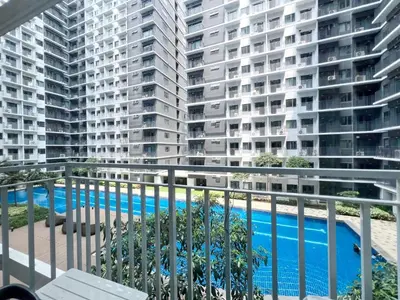 an apartment balcony with a swimming pool and tall buildings at Casa Liandro in SMDC shore 3 in Manila