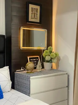a dresser with a mirror on a wall at Cozy Inn Azure in Manila