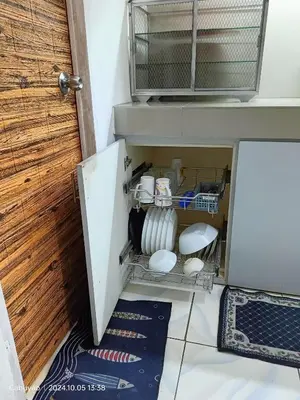 a cabinet with dishes in it next to a door at Family Airconditioned Room with Balcony & Parking in Cabuyao 2-storey house in Cabuyao
