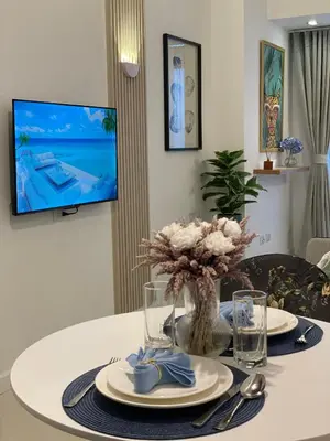 a dining room table with a tv in a living room at Cozy 1 bedroom condo in Uptown BGC in Manila