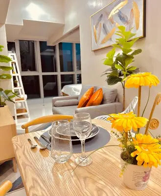 a dining room table with yellow flowers on it at 1BR Luxury unit in Uptown Parksuites -Walking distance to Malls in Manila