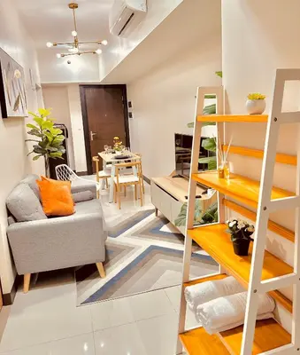 a living room with a ladder and a couch and a table at 1BR Luxury unit in Uptown Parksuites -Walking distance to Malls in Manila