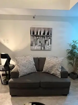 a couch in a living room with a painting on the wall at Stylish 1BR At Avant BGC in Manila