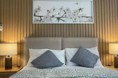 a bedroom with a bed with two pillows and a painting at Luxa House Staycation Tagaytay in Panungyanan