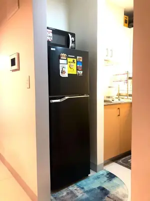 a black refrigerator in the corner of a kitchen at Cosy 1BR Uptown BGC with Balcony and Swimming Pool in Manila