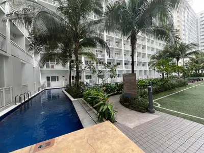 a swimming pool in front of a building with palm trees at Budget SHORE Family Suite 2 Bed WiFi Netflix MOA844 in Manila