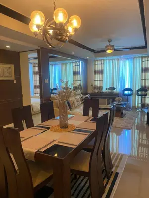 a dining room with a table and a living room at Elegant 2BR, 2 BA Suite Beside Eastwood Mall in Manila