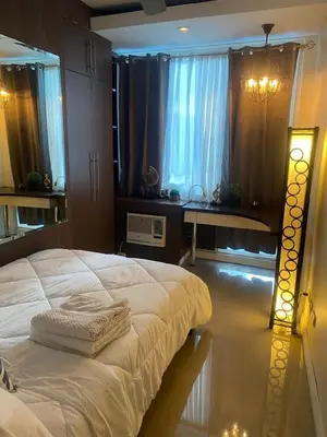 a bedroom with a white bed and a window at Elegant 2BR, 2 BA Suite Beside Eastwood Mall in Manila