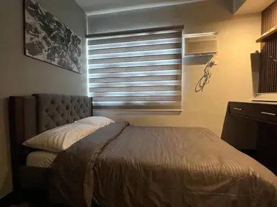a bedroom with a bed and a window with blinds at Fullerton Suites in Silang