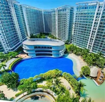 a large building with a large blue pool in front of tall buildings at 1BR Condotel at Azure Urban Resort Near Airport #AZ05 in Manila