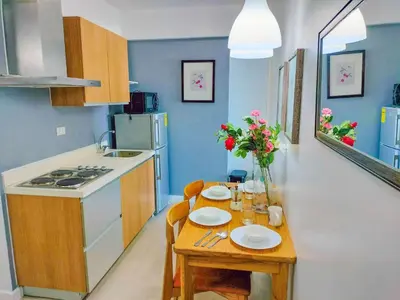 a small kitchen with a table with plates and flowers at Cozy 2 Bedroom With Blacony in Manila