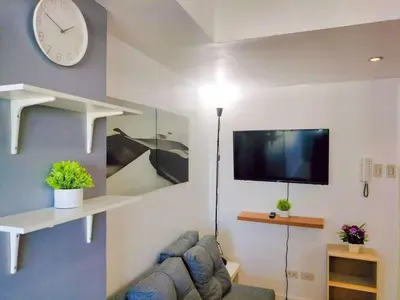 a living room with a couch and a clock on the wall at Cozy 2 Bedroom With Blacony in Manila