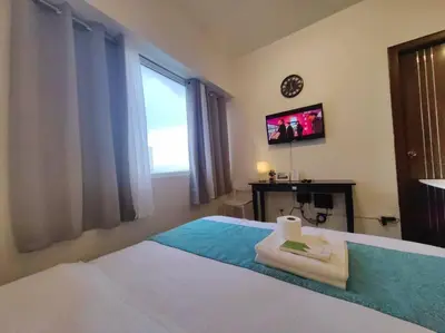 a bedroom with a bed with a tv and towels at 1BR Condotel Ridgewood Towers Taguig City #RW15 in Manila