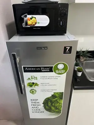 a microwave on top of a refrigerator with a sign at Cozy 1 Bedroom Makati Condo with Balcony Wifi in Manila
