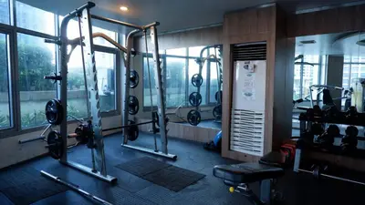 a gym with cardio equipment in a building with windows at New Cozy Condo in Eastwood in Manila